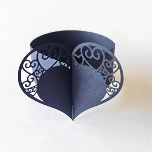 Detail of laser-cut black heart napkin ring featuring intricate hollow scroll patterns