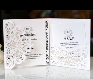 Detail of laser-cut wedding invitation set with white intricate lace cover and elegant cards