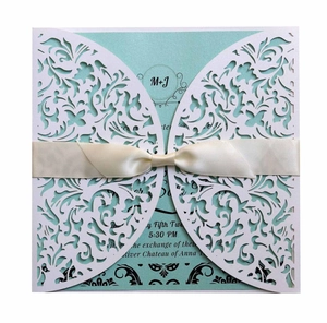 Detail of laser-cut floral invitation with mint green card and creamy silk ribbon bow