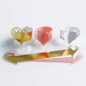 Detail view of laser cut paper napkin rings in gold, pink and white with heart patterns