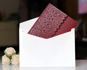 Detail of laser-cut floral patterns on pink invitation card with elegant white envelope