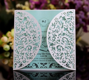 Detailed laser-cut vine patterns on white wedding invitation sleeve with blue card