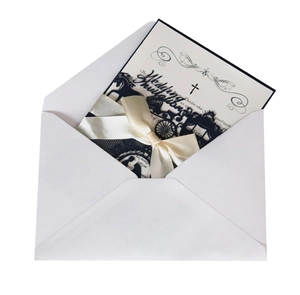 Macro view of white envelope with laser cut black wedding card and cream ribbon bow