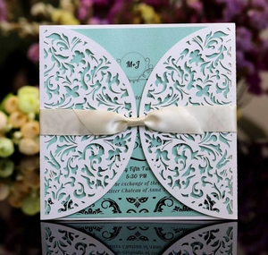 Laser-cut floral wedding invitation with mint green insert and elegant cream ribbon