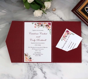 Burgundy laser-cut wedding invitation set with watercolor floral cards on marble backdrop