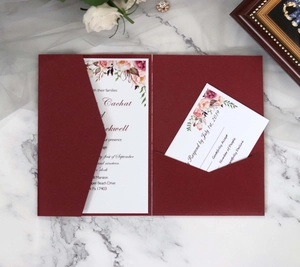 Macro detail of burgundy laser-cut wedding invitation set with floral white cards