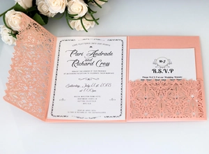 Detail of laser-cut lace wedding invitation set with peach pink floral shell and white inserts