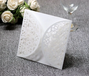 Detailed laser-cut floral pattern on white wedding invitation sleeve with elegant texture