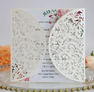 Detail of laser-cut vine patterns on elegant off-white wedding invitation covers