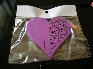 Detail of purple laser-cut heart place cards with floral patterns for wedding glasses
