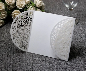 Detail of white laser cut floral wedding invitation cover with intricate hollow pattern