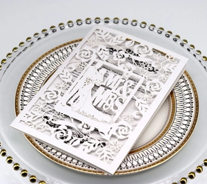 Elegant white laser cut wedding invitation with Mr & Mrs floral design on a gold plate