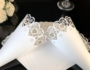 Close-up of laser-cut white wedding confetti cones with delicate heart-shaped patterns
