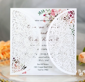 Macro detail of laser-cut rose hollow invitation with floral insert and pearl accents