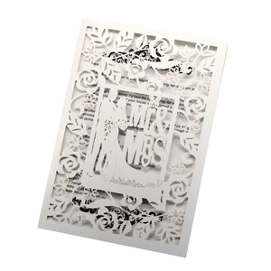 Detail of white laser-cut wedding invitation featuring Mr & Mrs and rose patterns