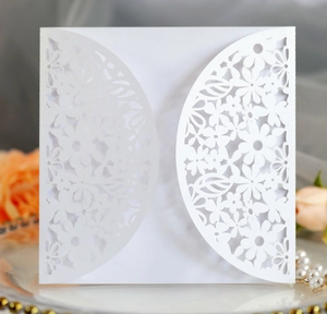Detailed laser-cut white wedding invitation cover with intricate floral and leaf patterns