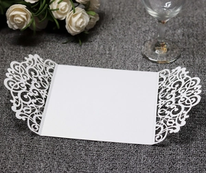 Detail of white laser cut invitation card with lace patterns on grey texture