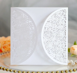 Macro shot of laser-cut white rose invitation card with delicate hollow floral patterns