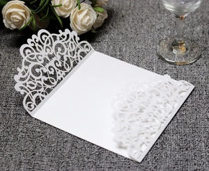 Detail of laser-cut wedding invitation cover with elegant white floral vine patterns