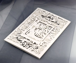 Macro detail of laser-cut wedding invitation featuring elegant floral patterns and Mr & Mrs text