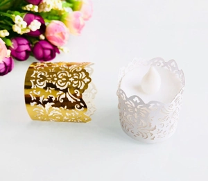 Detail of laser-cut gold and white tea light candle wraps with elegant floral patterns