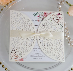 Detail of laser-cut invitation sleeve with floral pattern and satin bow decoration
