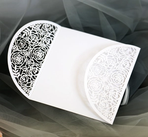 Detailed macro of white laser-cut wedding invitation featuring elegant rose flower patterns