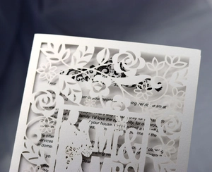 Detail of cream white laser cut wedding invitation with rose frame and bride groom silhouette