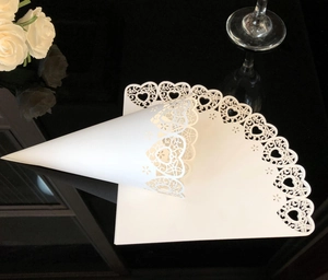 Detailed laser-cut heart lace pattern on white paper cones for wedding confetti use