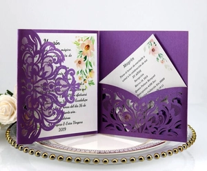 Close-up of laser-cut purple lace wedding invitation with floral insert on elegant plate
