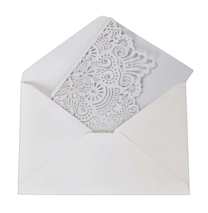 Close-up of white laser-cut wedding invitation featuring intricate hollow floral patterns