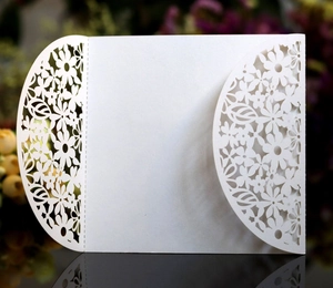 Elegant white laser-cut wedding invitation featuring intricate floral and leaf patterns