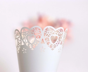 Detailed view of white laser-cut paper cone with delicate heart and floral hollow patterns