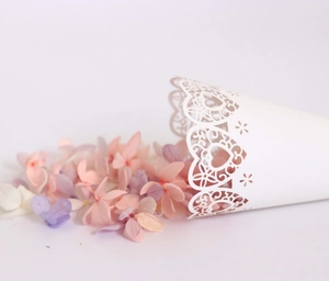 Detail of laser-cut white heart and flower pattern on paper wedding confetti cone