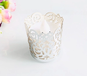 Detail of white laser-cut filigree tea light wrap with warm LED flickering candle inside