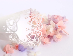 Close-up of laser-cut heart pattern on white wedding cone with dried flower petals