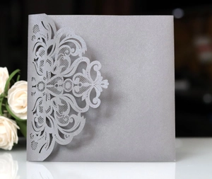 Close-up of laser-cut lace floral pattern on silver pearlescent paper invitation cover
