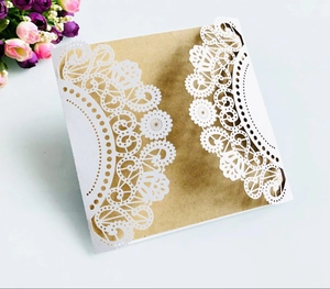 Detailed close-up of laser-cut lace wedding invitation with kraft paper insert and roses