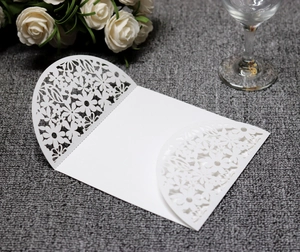 Detail of white laser-cut floral invitation cover with intricate hollowed-out leaf patterns