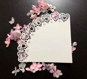 Detail of white laser-cut paper cone with delicate heart patterns on black background