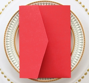 Detail of red kraft paper invitation envelope with V-flap on vintage decorative plate