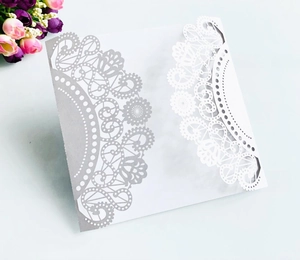 Detailed laser-cut lace pattern on pearlescent cardstock for wedding invitations