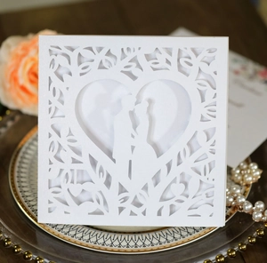 Macro detail of laser-cut heart and couple silhouette on pearlescent wedding invitation