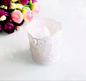 Macro detail of white laser-cut paper tea light holder with rose patterns and LED candle