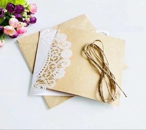 Detail of kraft paper invitation with laser cut white lace design and jute rope twine
