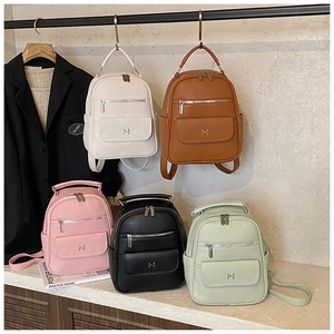 Detail showing five colors of leather mini backpacks with multiple zipper compartments