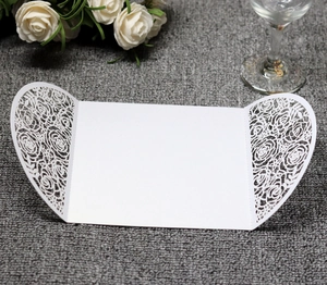 Detail of white laser-cut invitation sleeve featuring intricate rose floral patterns