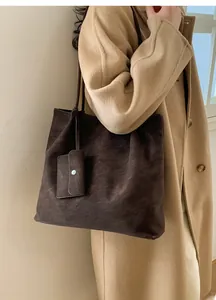 Detail of dark brown tote bag with small square pouch accessory on khaki wool coat