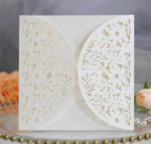 Close-up of laser-cut ivory wedding invitation cover with intricate floral patterns