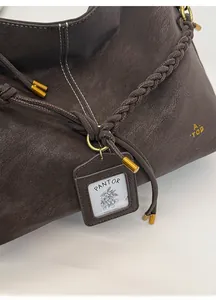 Close-up of brown vintage tote bag featuring woven straps and golden metal hardware details
